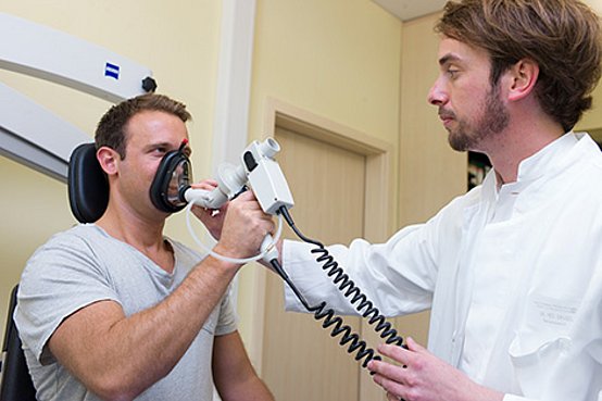 Arzt setzt Patientem spezielle Atemmaske zur Messung des Atemwiderstandes auf